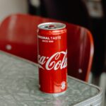 Coca-Cola original taste soda can on edge of gray table